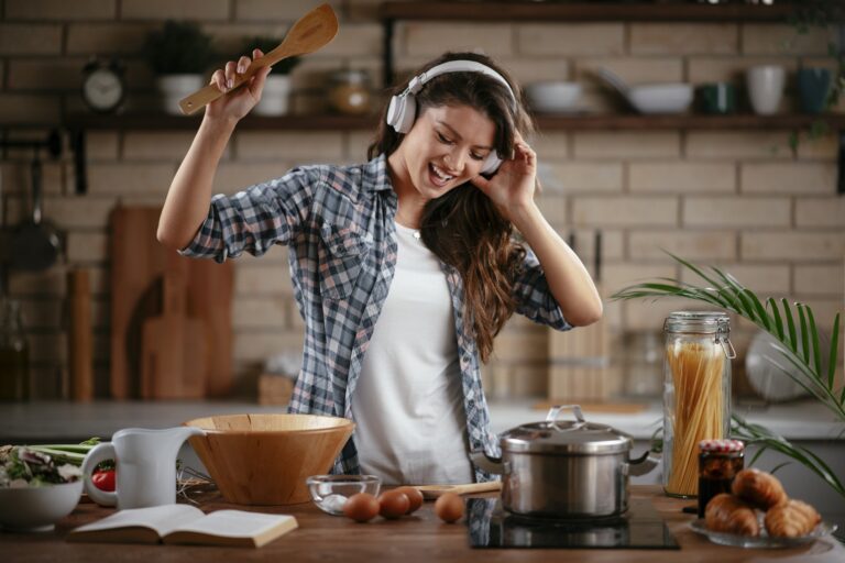 Beautiful woman listening the music while cooking at home